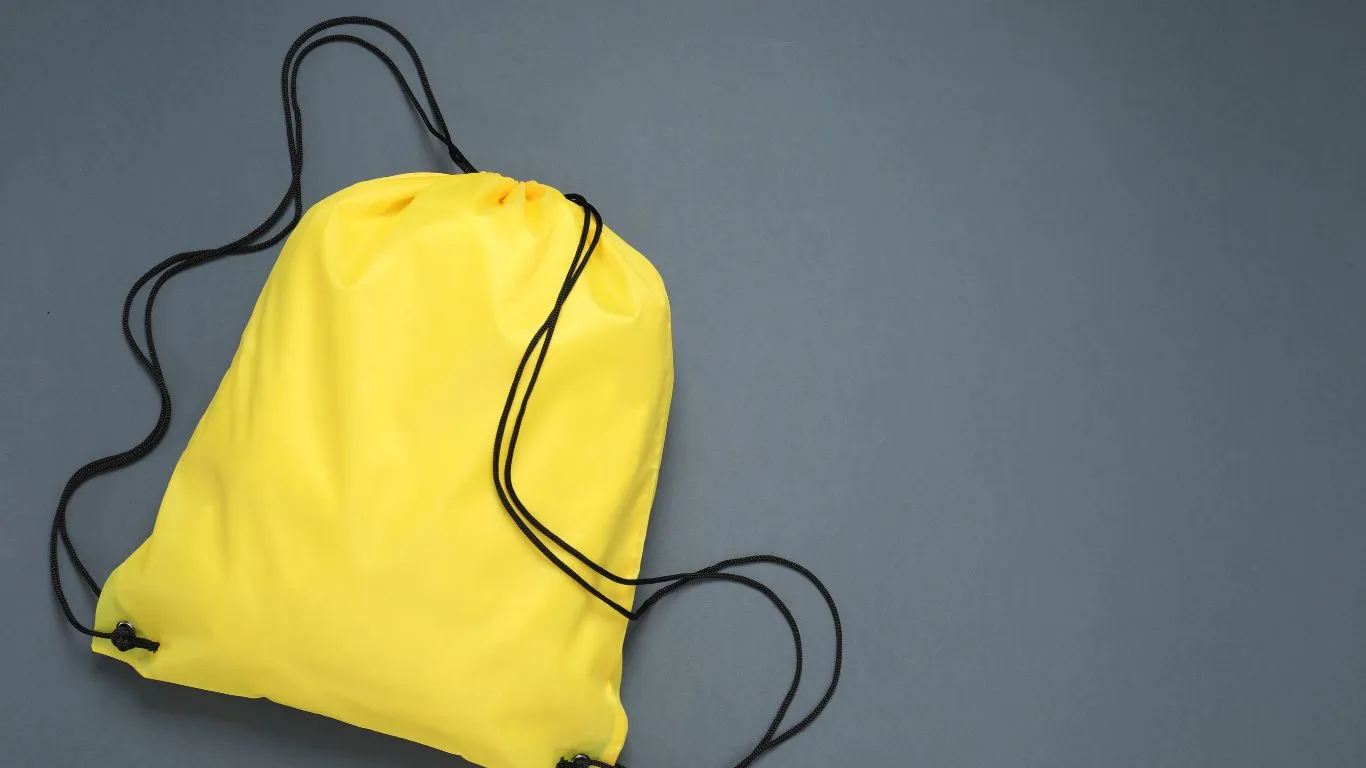 Tas serut kuning bertali hitam di atas latar abu-abu